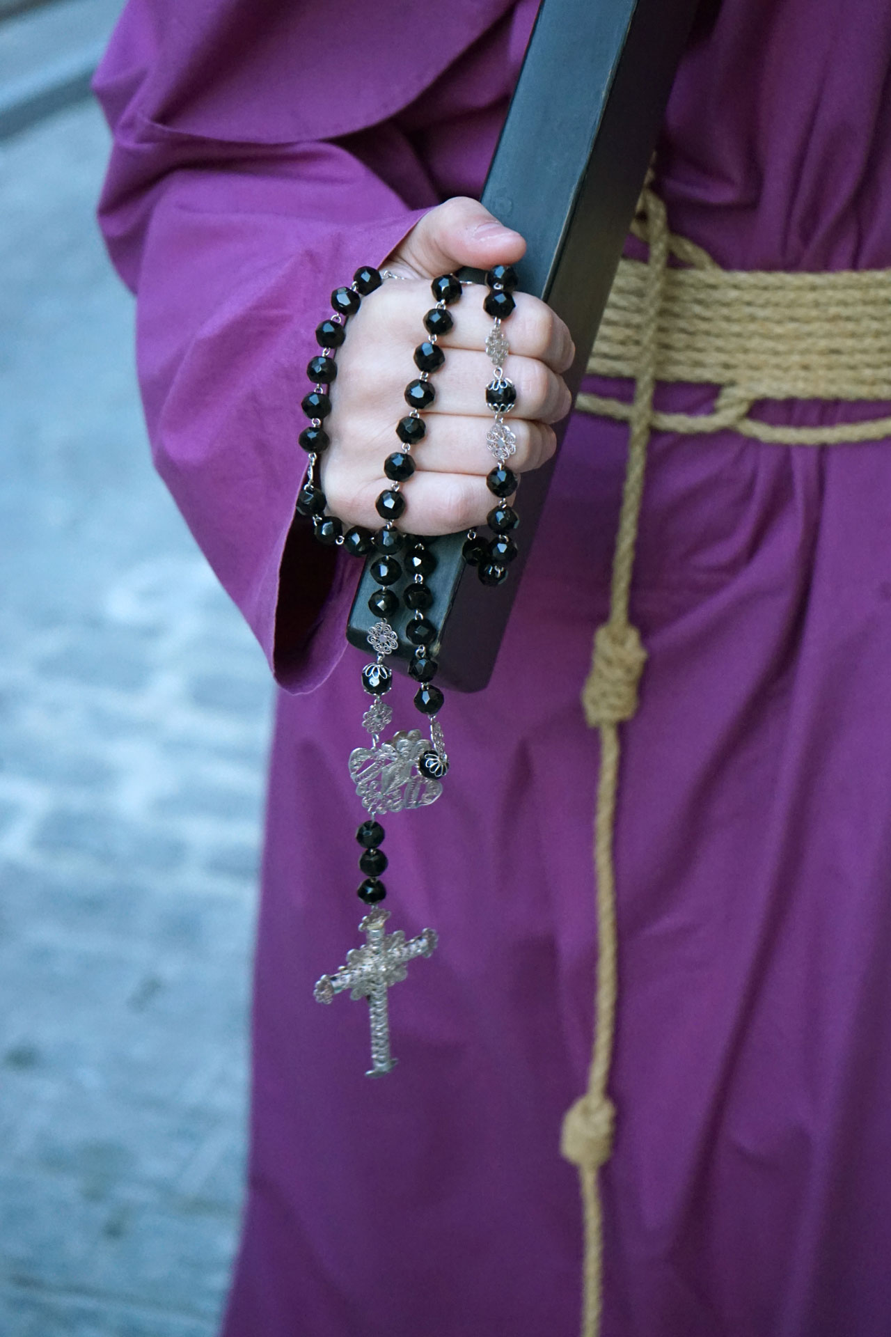 Primer plano e la mano de un cofrade portando un rosario